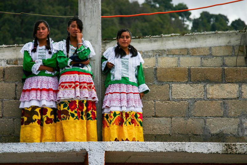 Three teenage girls dress in traditional Mexican outfits