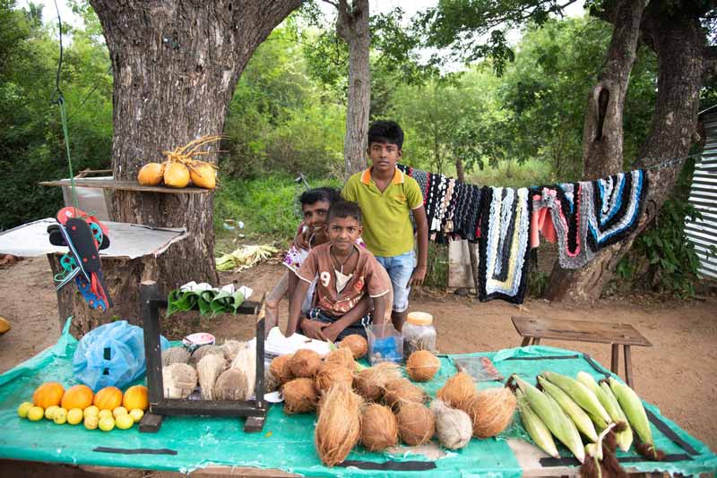 A family sits on ground while selling their produce