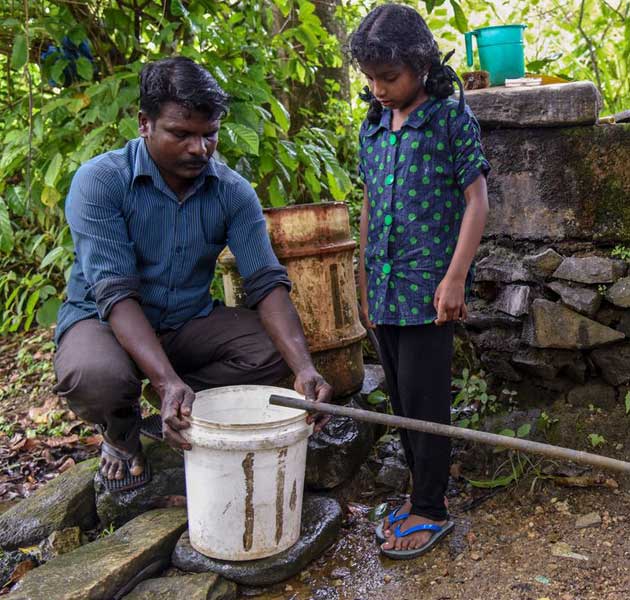 A father and his daughter collecting water in a bucket