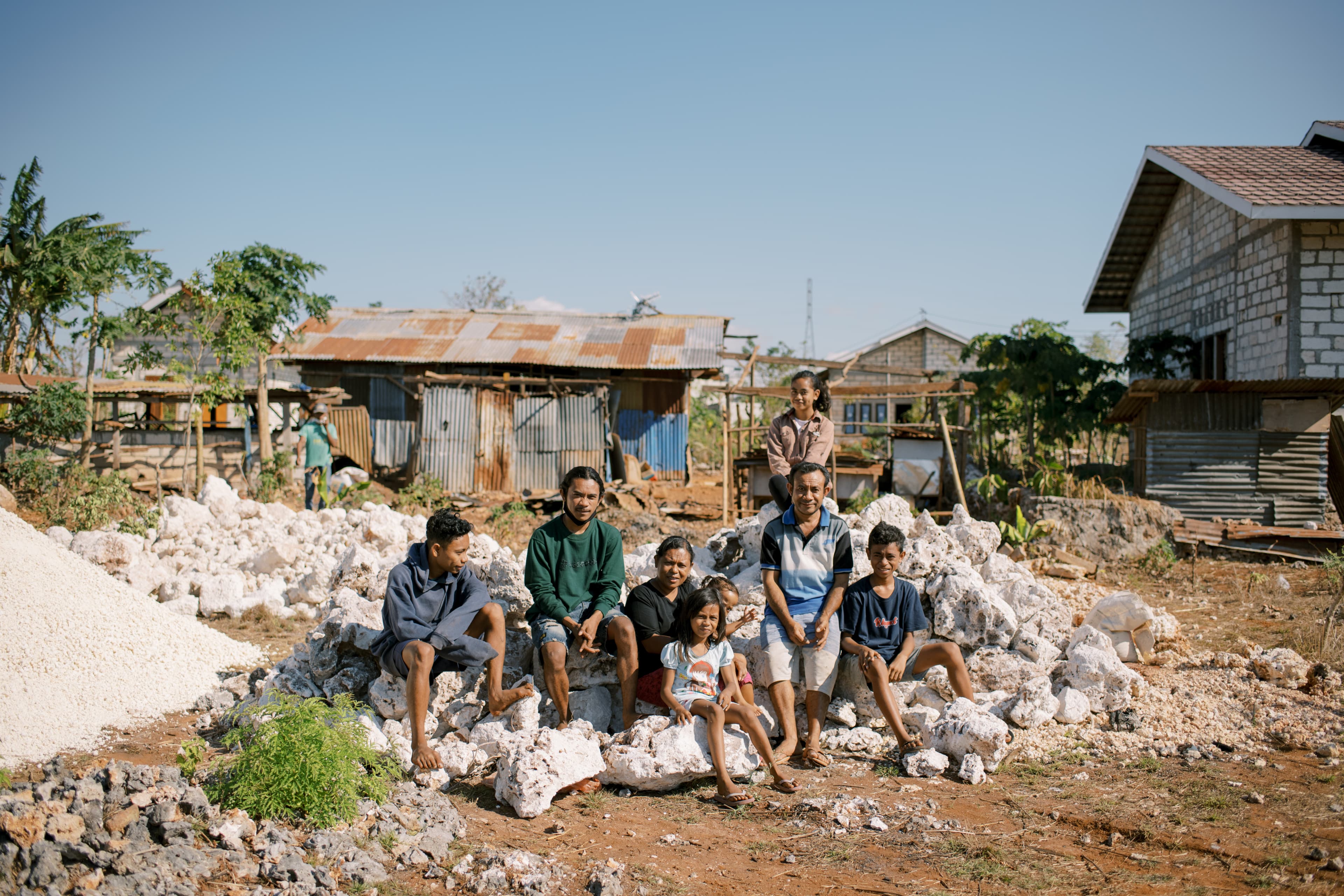 A family sits among rock and rubble.