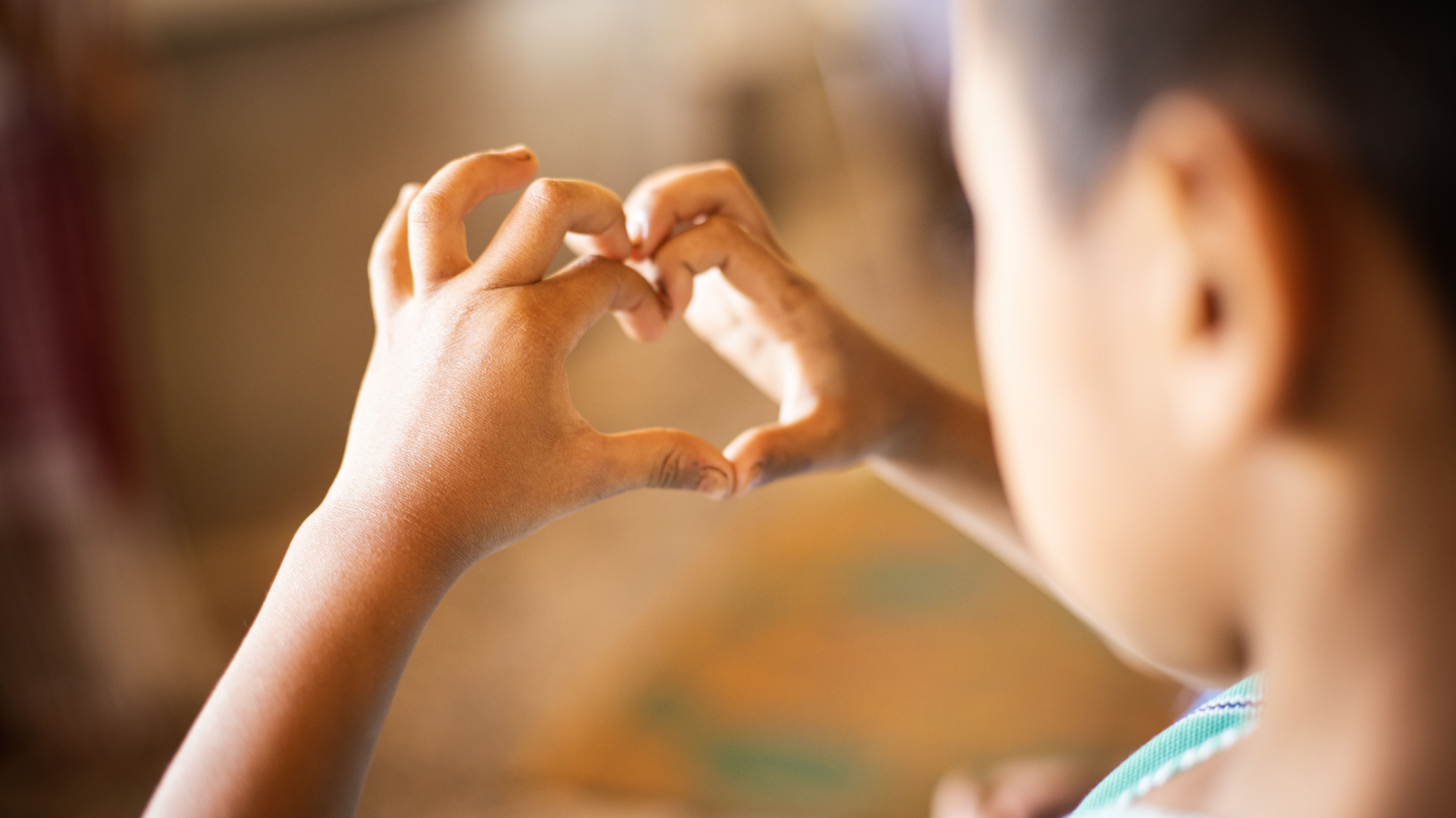 A young boy’s hands making the shape of a heart.