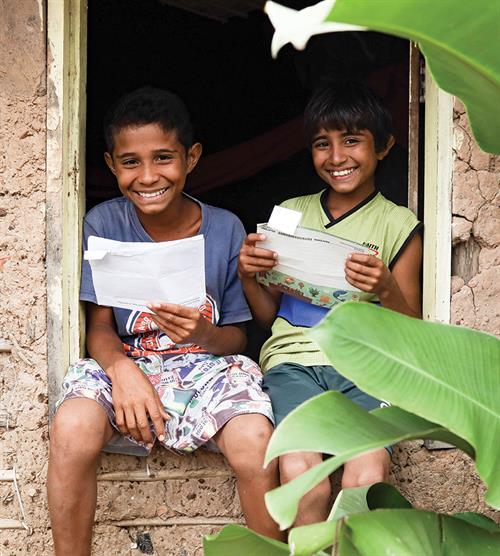 2 smiling children holding pieces of paper