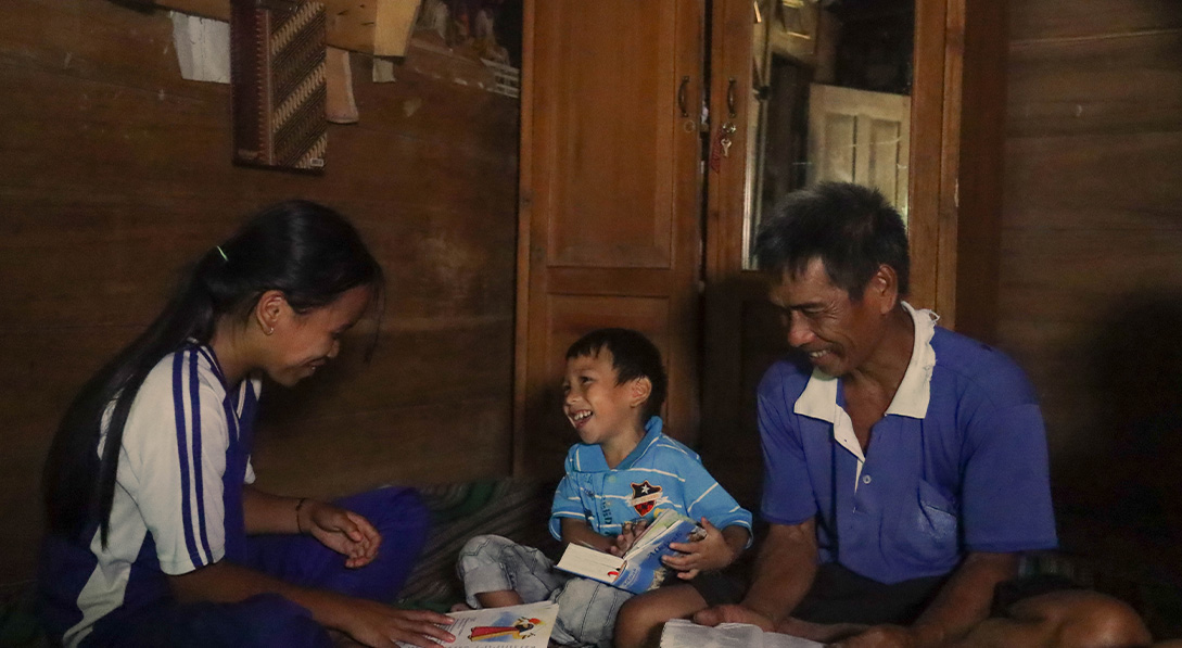  A dad and his two children sit together in the floor while reading their Bibles together.