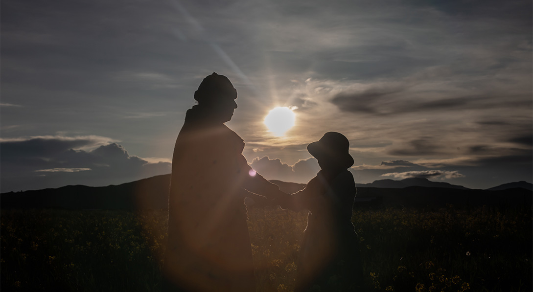 The silhouette of a mom and child in front of a bright sun.