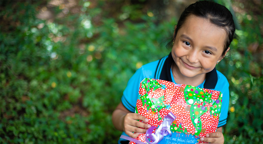 child smiles and holds colorful gift