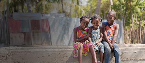 Young girls in a field smiling and giving thumbs up