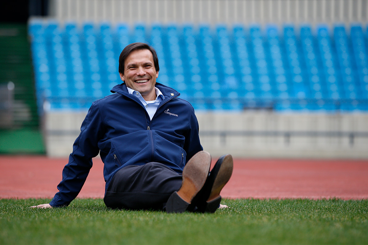 Jimmy Mellado sits on the turf in the Olympic stadium in Korea and smiles for the camera.