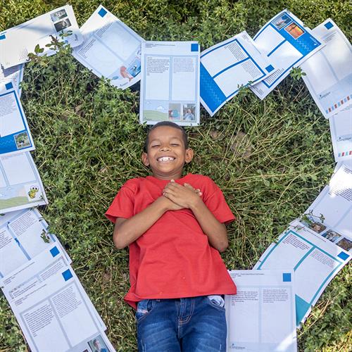 Child laying on the ground with letters in a heart shape