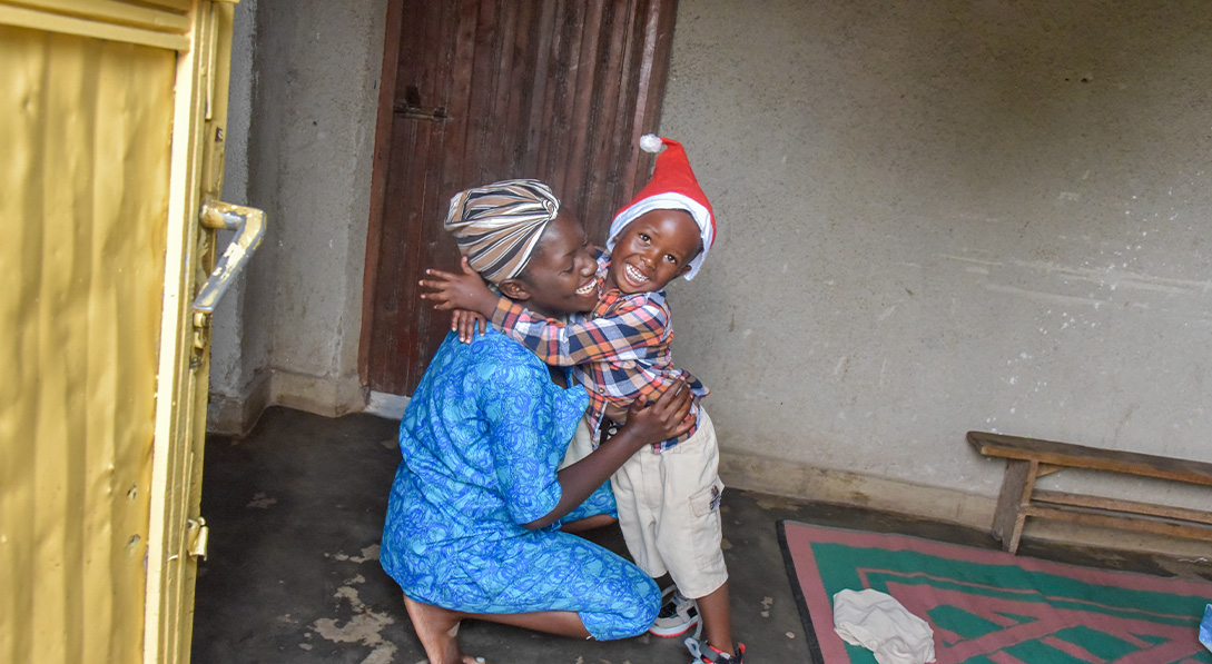 Child in santa hat hugs lady