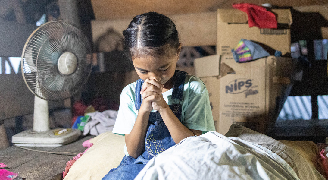 little girl folds hands to pray