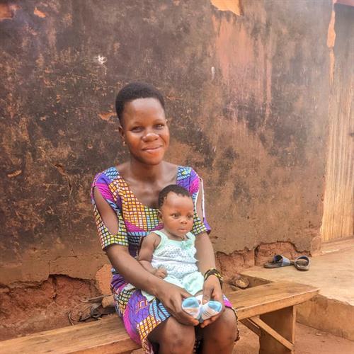 a mother sits on a bench holding her toddler in her lap