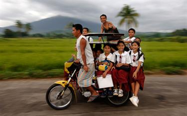 Children ride a motorcycle taxi to school