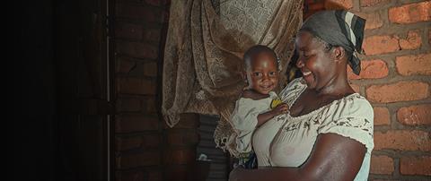 A mother holds her baby and smiles