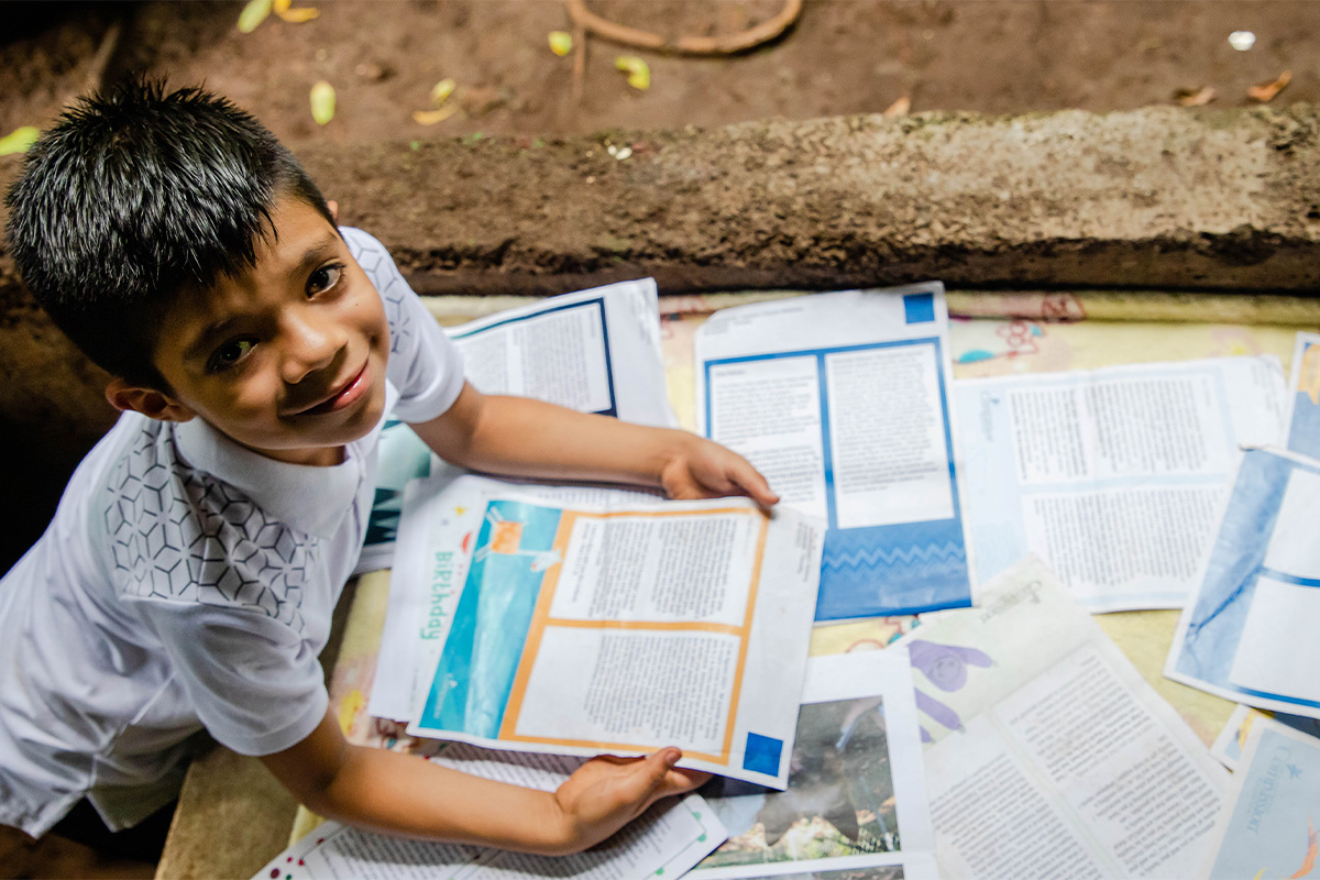 Young boy grins with many letters displayed.