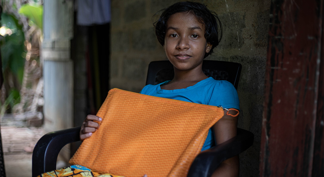 A young girl holds a bright orange letter case.