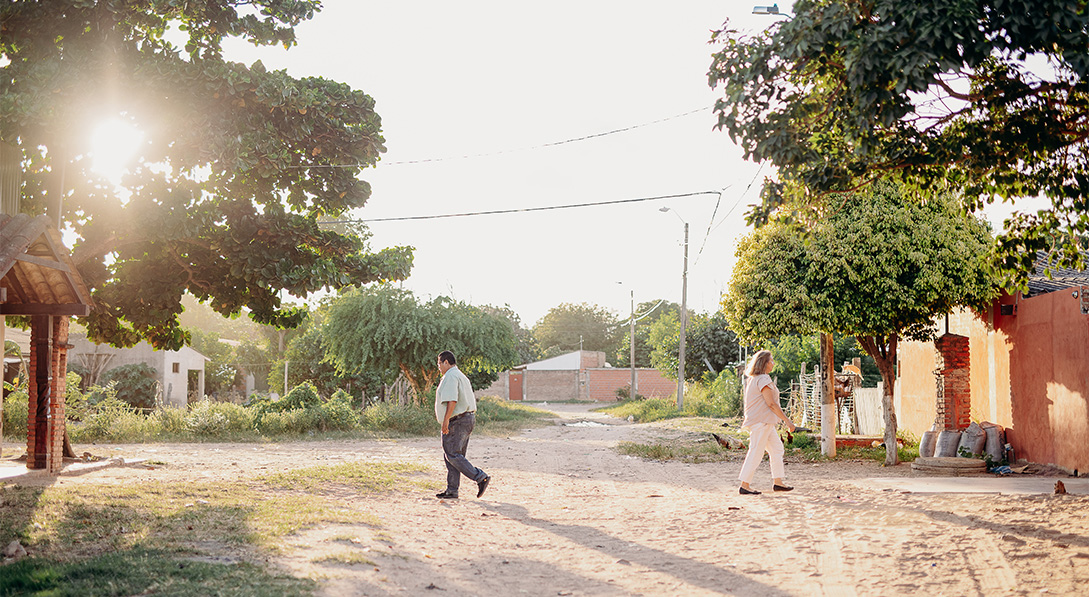 Pastor Raul and Sister Graciela walk away from each other down a dirt path.