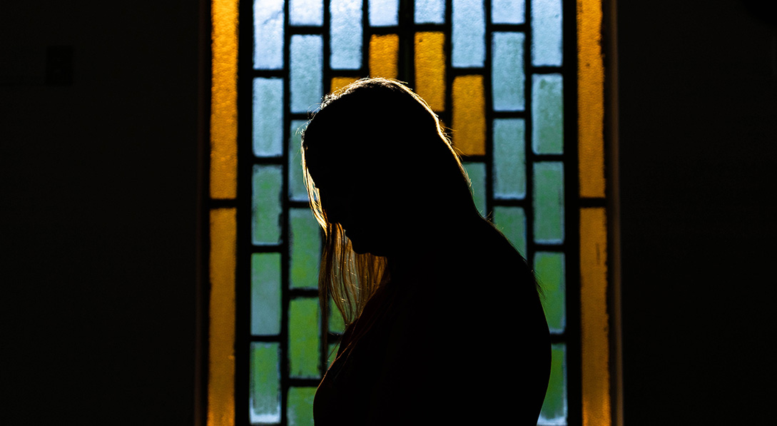 A silhouette of a child protection officer in front of a stained glass window.