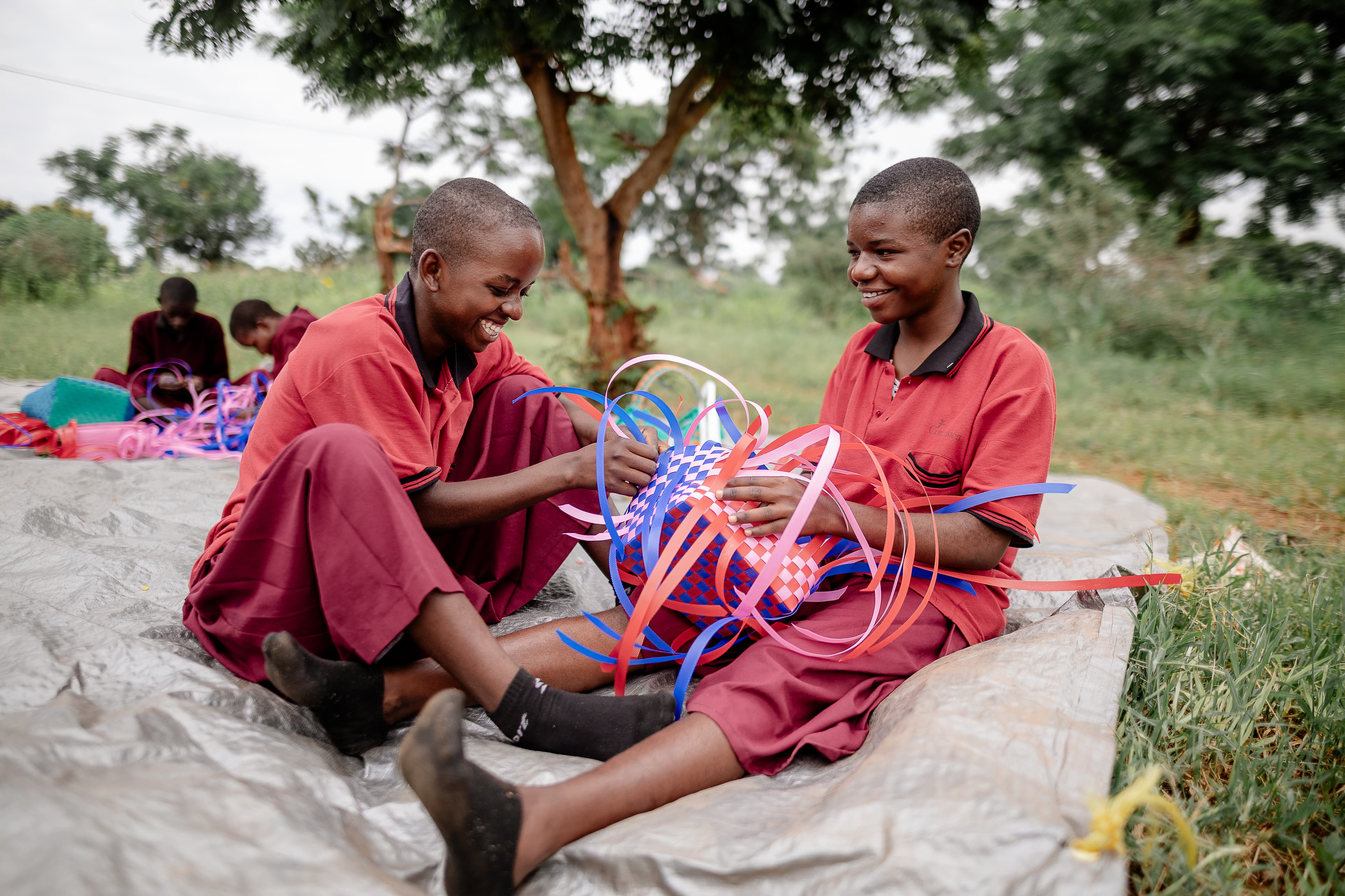 Two young girls are sitting and laughing together as they play with craft.