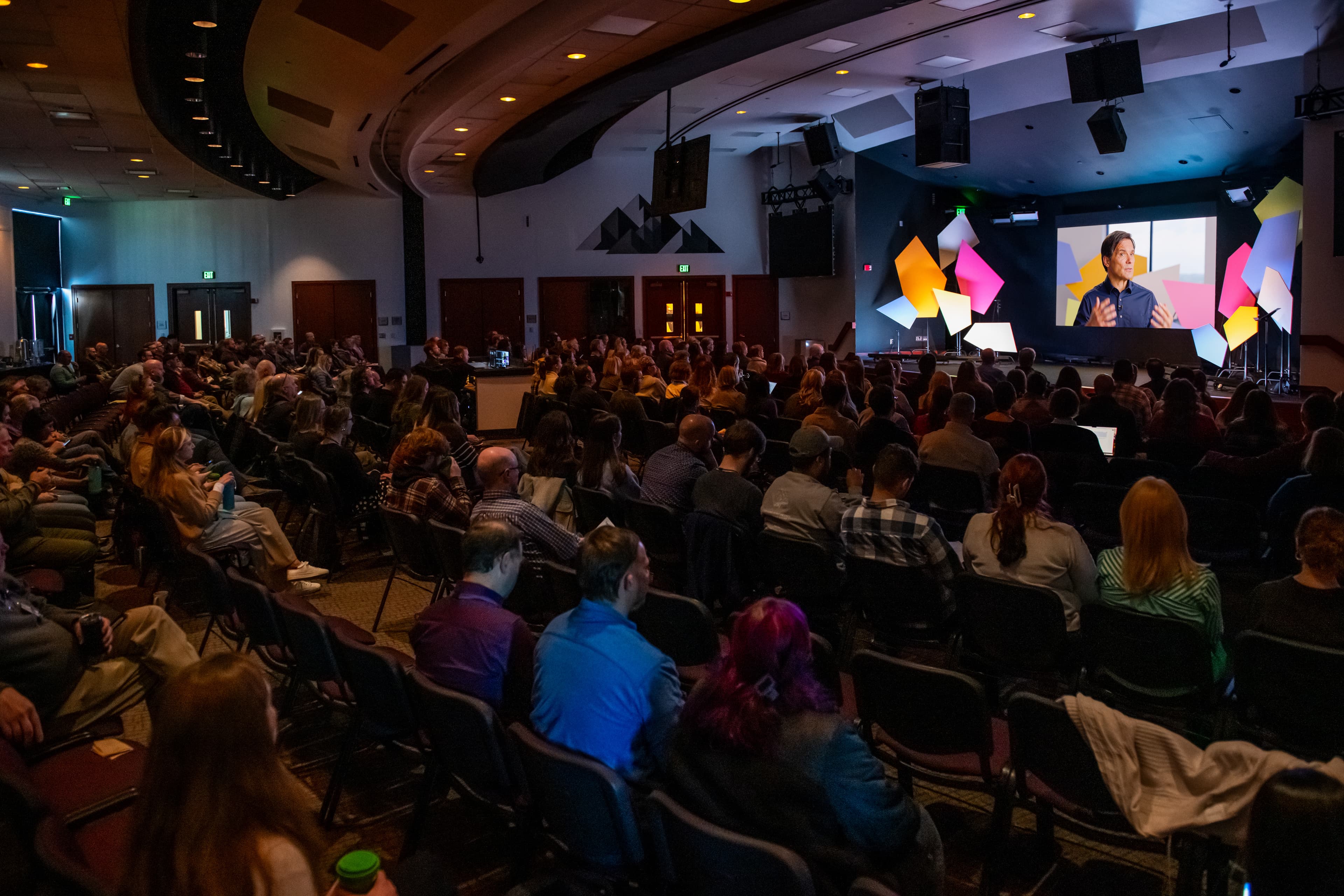 An auditorium full of people sitting in chairs.