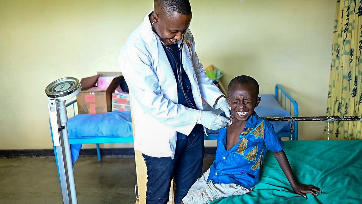 A young African boy giggles as a doctor places a stethoscope on his chest.