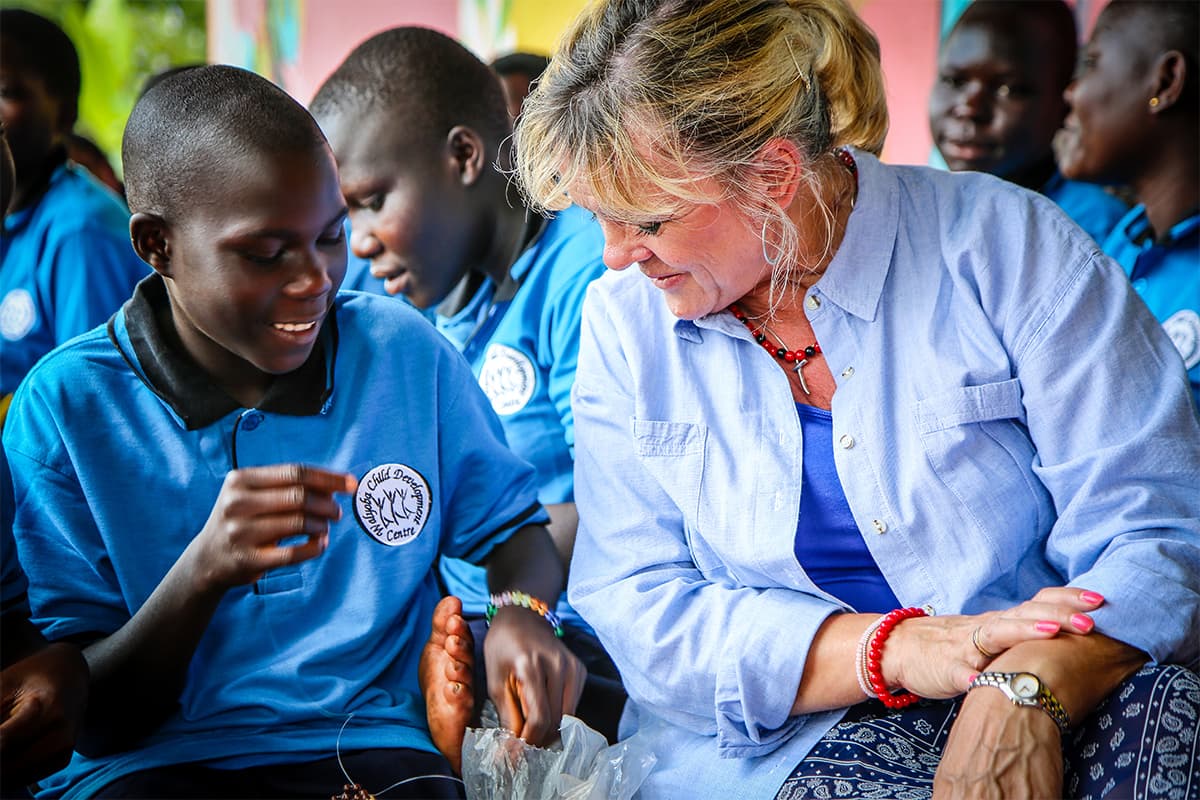 A woman is talking as she sits next to a child in the classroom.