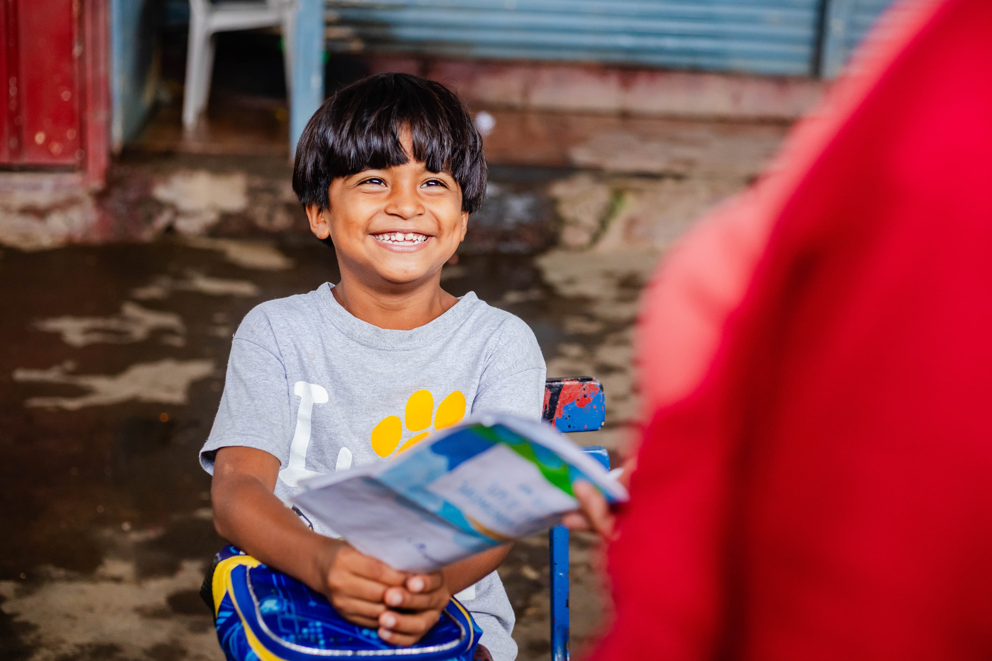 A young boy smiles brightly while holding a letter in his hands.