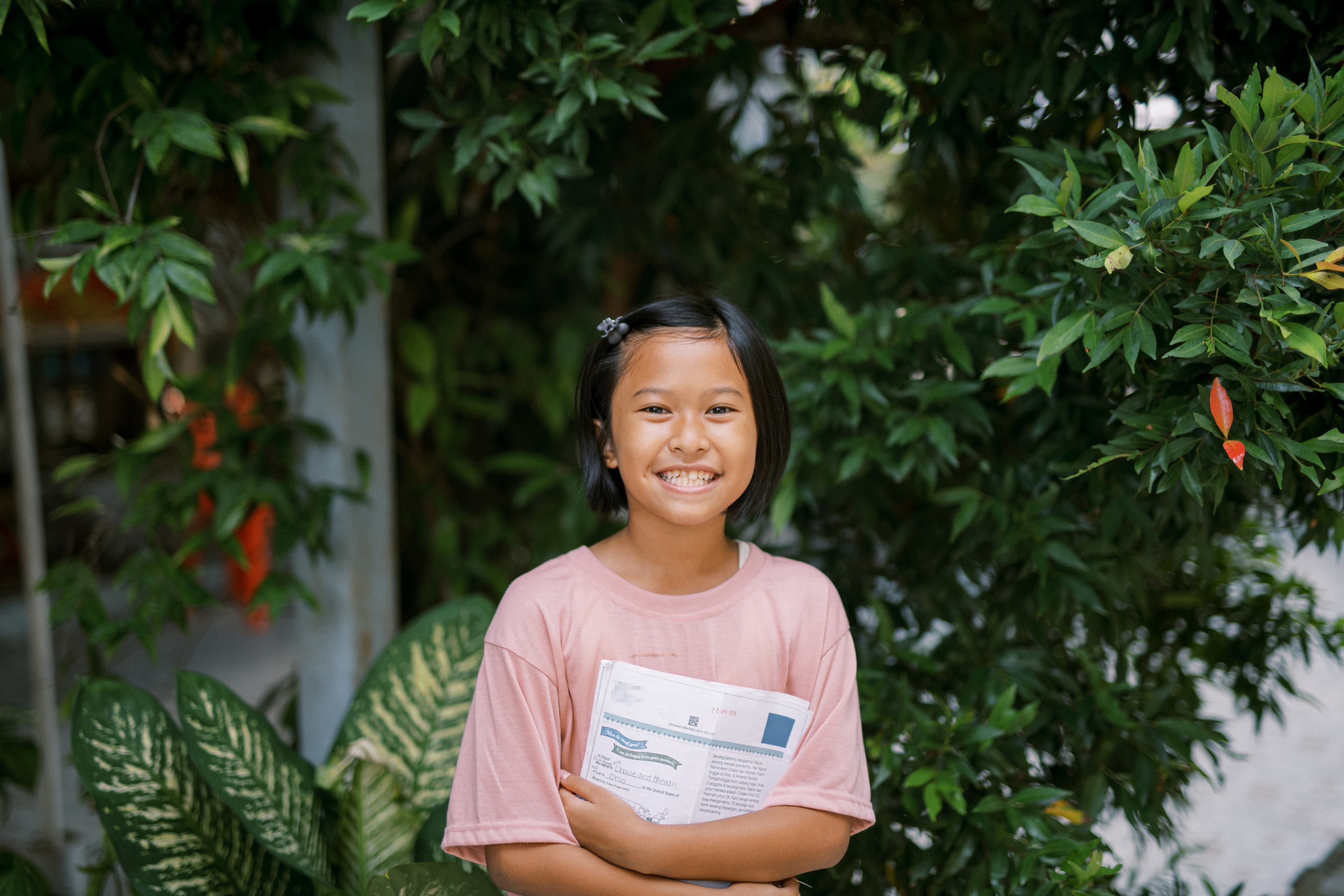 A young girl is smiling and holding a letter from her sponsor